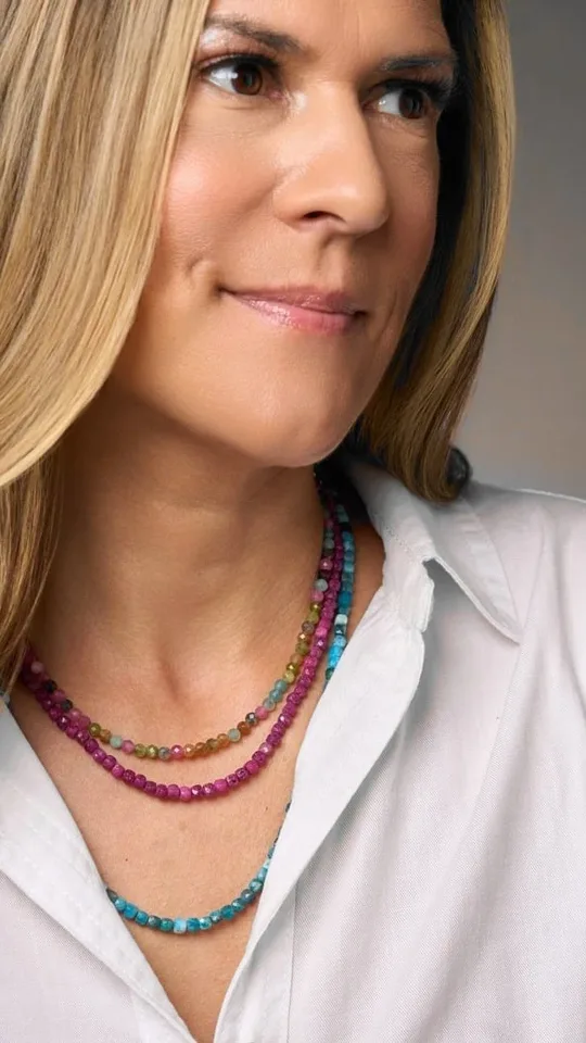 Magda Loczi in a white shirt wearing layered pink, green and blue gemstone strands